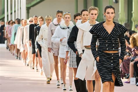 Un desfile de moda vintage con coches clásicos de fondo
