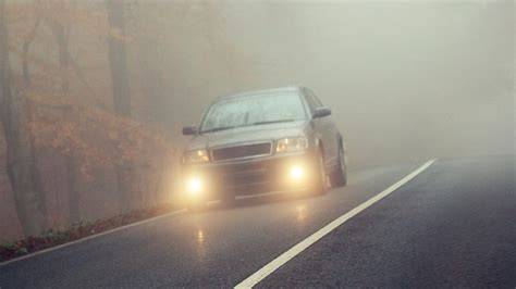 Un coche Opel circulando en condiciones de niebla con los faros antiniebla encendidos.