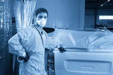 Técnico preparando un coche para pintar, cubriendo partes no deseadas