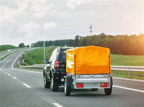 Ilustración de un coche con remolque realizando un giro cerrado, mostrando la necesidad de abrir la trayectoria
