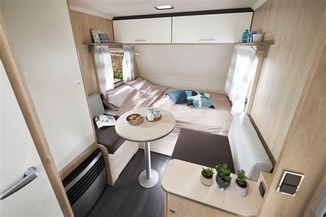 Interior de una caravana pequeña con cama doble y comedor convertible